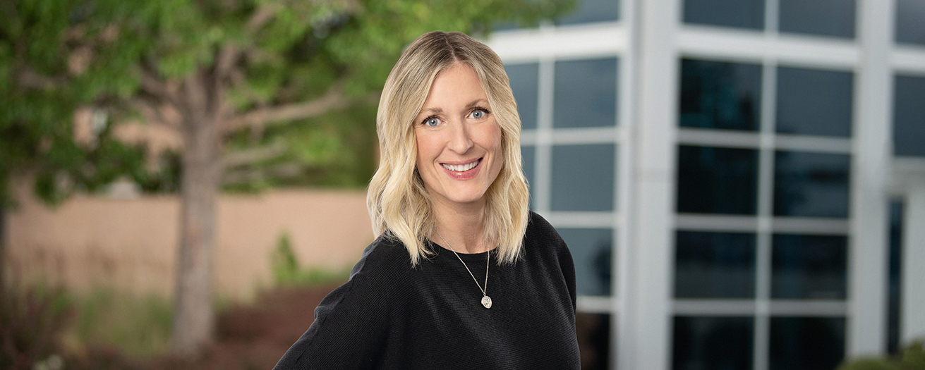 Photo of Angie Henderson in front of a tree and building