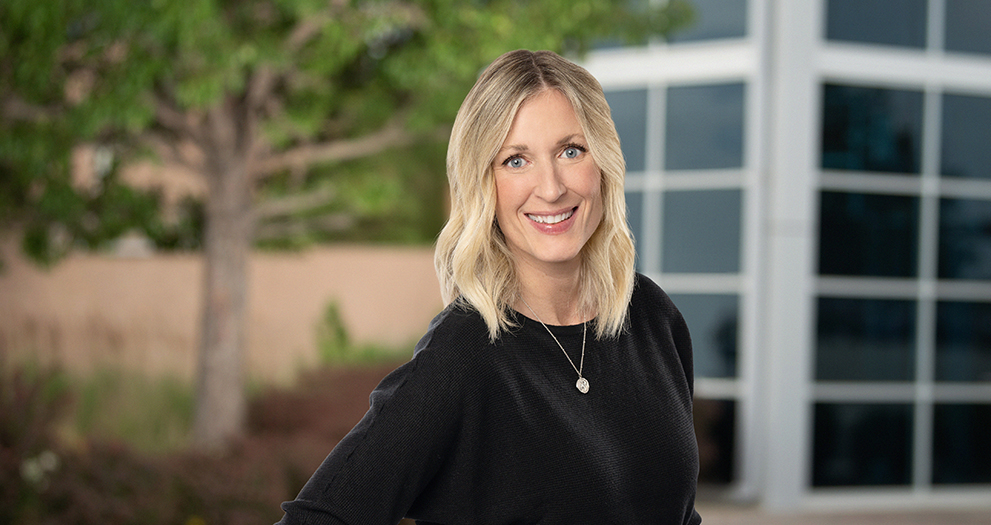 Photo of Angie Henderson in front of a tree and building