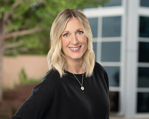 Photo of Angie Henderson in front of a tree and building