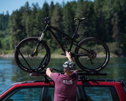 Photo of a man in an STCU shirt putting a mountain bike on top of an SUV