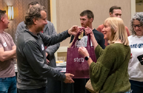 A man handing an STCU bag to a woman