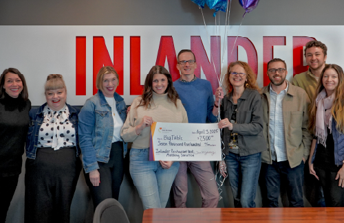 Eight people standing together holding up a large check 
