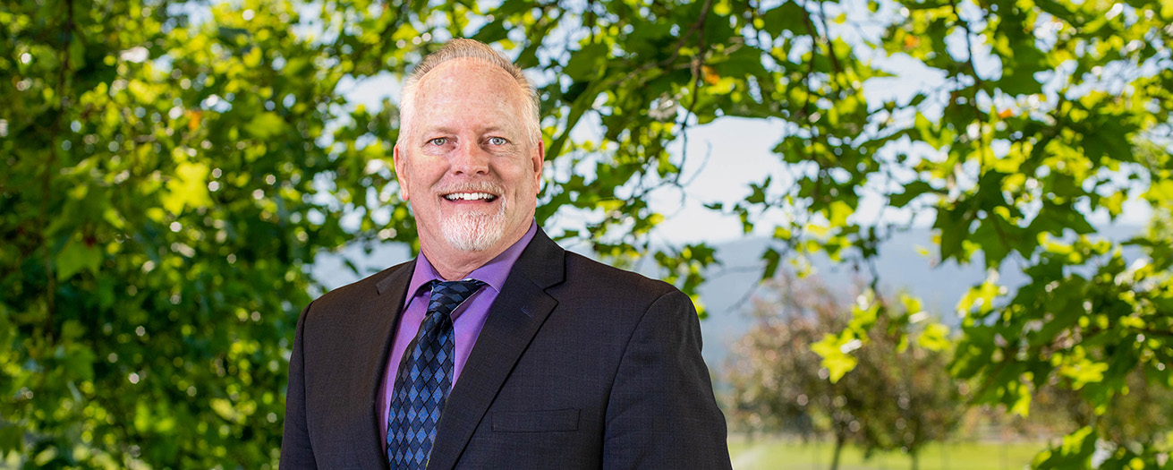 A photo of Greg Templeton outside, with a tree in the background