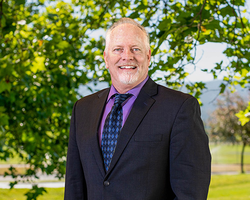 A photo of Greg Templeton outside, with a tree in the background