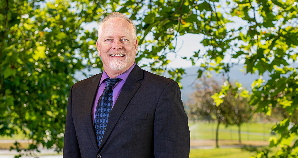 A photo of Greg Templeton outside, with a tree in the background