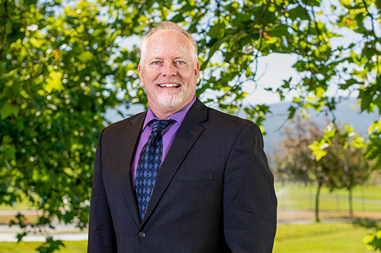 A photo of Greg Templeton outside, with a tree in the background